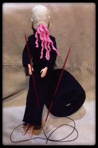 an Ood doll with yarn and knitting needles